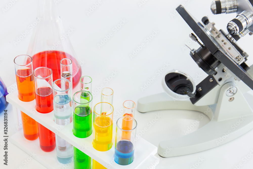 Poster Test tubes in a stand and a microscope on a white table