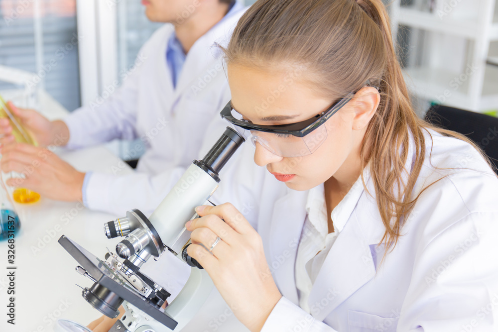 Poster male and female scientists working in a science laboratory with various equipment in the laboratory.