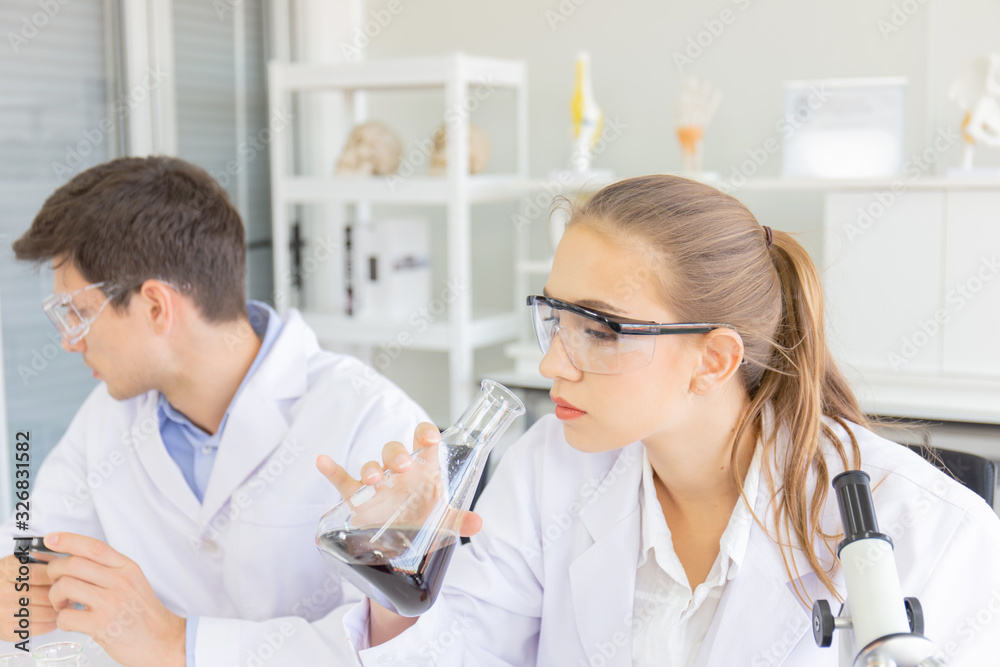 Poster male and female scientists working in a science laboratory with various equipment in the laboratory.