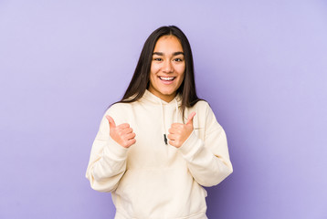Young woman isolated on a purple background raising both thumbs up, smiling and confident.