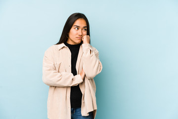 Young woman isolated on a blue background who feels sad and pensive, looking at copy space.