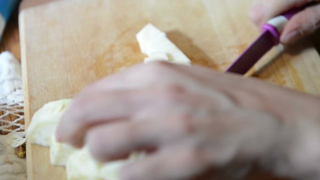 slicing and Cutting celery root in pieces on a cutting board.