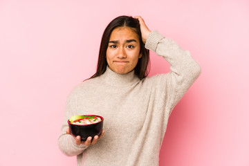 Young asian woman holding a noodles isolated being shocked, she has remembered important meeting.