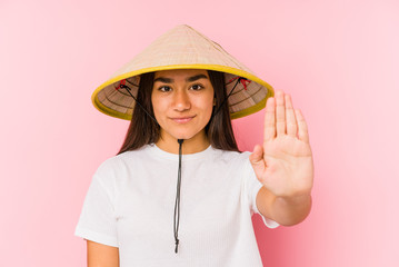 Young asian woman wearing a vietnamese hat isolated Young asian woman wearing a vietnamin hatstanding with outstretched hand showing stop sign, preventing you.