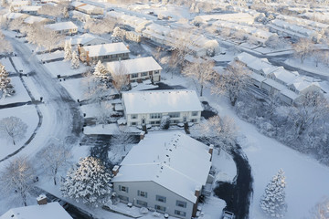 Aerial view of residential houses covered snow at winter season. Establishing shot of american neighborhood, suburb.  Real estate, drone shots, sunny morning, sunlight, from above.