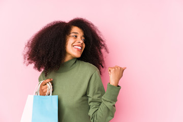 Young afro woman shopping isolated Young afro woman buying isolaYoung afro woman holding a roses isolated points with thumb finger away, laughing and carefree.< mixto >