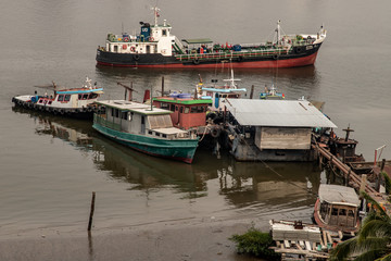 Cargo ships in the middle Chao Phraya river near the small pier.