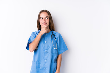 Young nurse woman isolated looking sideways with doubtful and skeptical expression.