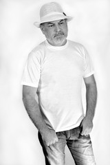 black and white photo of a man with a white beard in jeans, casual white shirt and hat on white background
