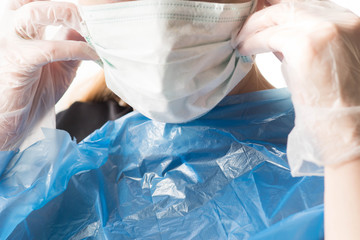Woman, doctor, nurse putting on ffp2 surgical mask and gloves to protect herself from 2020-ncov...