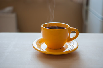 Yellow cup with steaming coffee in the kitchen in the morning. Drink