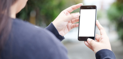 Cropped shot view of woman hands holding smart phone with blank copy space screen for your text message or information content, female reading text message on cell telephone during in urban setting.