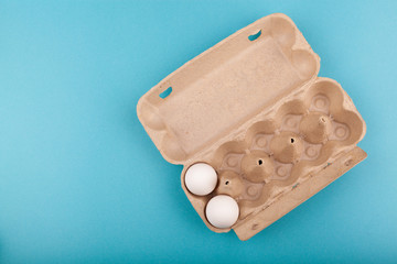 Egg Chicken eggs. Top view of an open gray box with white eggs. Isolated on a blue background. The concept of a healthy lifestyle, getting pure protein. Proper Breakfast. Two eggs.