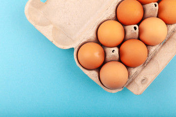 Egg Chicken eggs. Top view of an open gray box with brown eggs Isolated on a blue background. The concept of a healthy lifestyle, getting pure protein. Proper Breakfast. Dissati eggs.