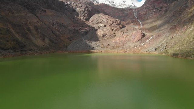 Green lake in peruvian andes, smoth fly over the water