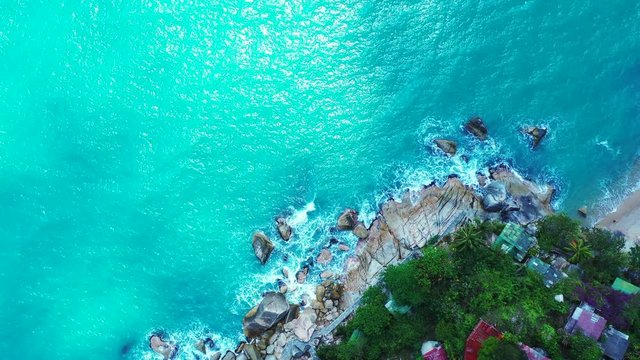 Koh Phangan, Thailand. Rocky coast with bungalows on the cliff edge. rough sea waves crashing on the stones