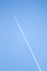 White track from an airplane in the blue sky. Trail of a winged passenger plane in a clear blue sky