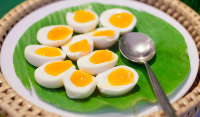 Selective Focused Halved Boiled Chicken Eggs served in green banana leaf tray. Traditional Thai Street Comfort Food, Asian Cuisine, Delicacy, Culture, Cooking, Snack, Indulgence and Nutrition concept