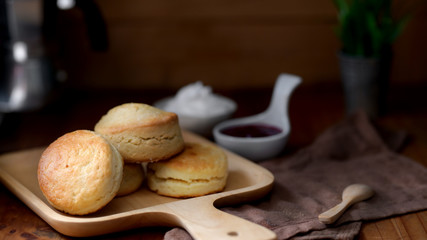 Scones on wooden tray with strawberry jam and clotted cream
