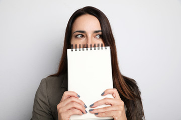 Close-up portrait of business woman hiding her face with a block note. isolated.
