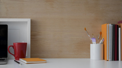 Cropped shot of workspace with laptop, books, painting tools and copy space on wooden desk