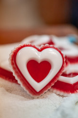 A red piece of handmade soap in the shape of a heart with a white insert, lying on a white towel...