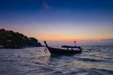 view seaside evening of a long-tail boat floating in the sea with sun shine and cloudy sky background, sunset at Lipe island, Satun, southern Thailand.