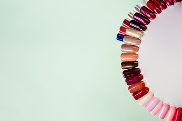 Background of multicolored nail polish samples. Top view of the color palette of nail services in beauty salon. Fashion manicure. Gel lacquer. Selective focus. Copy space.
