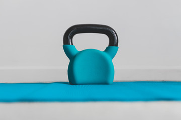 Fototapeta na wymiar home gym concept, blue yoga mat with kettlebell shot at shallow depth of field from low perspective