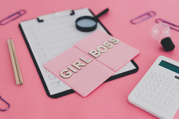 equal opportunities Girl Boss text on top of pink notebook on business office desk with to do list and mixed stationery on pink background