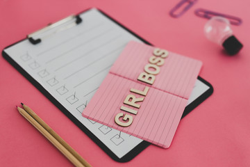 equal opportunities Girl Boss text on top of pink notebook on business office desk with to do list and mixed stationery on pink background