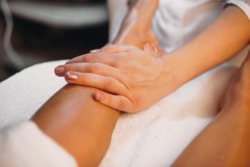 Obraz na płótnie Canvas Caucasian therapist is massaging the client's legs during a skin care procedure