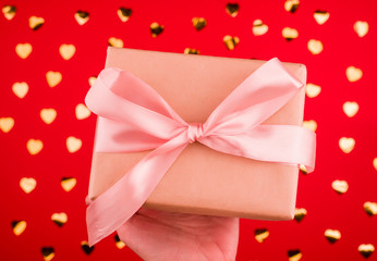 A beautiful gift box with satin ribbon in hand.