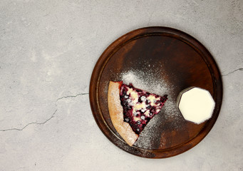 Sweet pie with cottage cheese and black currant served on a wooden board on a light background. Top view, flat lay.