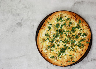 Pizza with olives and feta served on a wooden board  on a light background. Top view, flat lay.