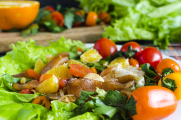 delicious spring salad with fish and vegetables on a white plate decorated with tomatoes, herbs and sweet peppers close-up