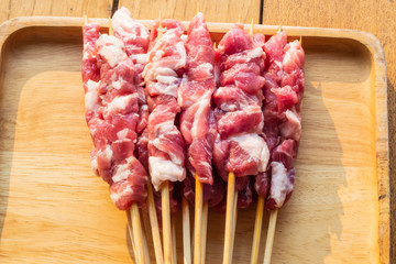 Fresh pork skewers in a wooden tray on a wooden table
