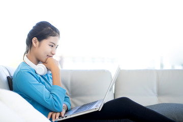 Asian young woman using laptop computer and eye looking to monitor, relaxing working at home concept