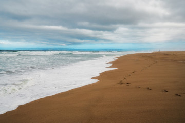Scenic seascape. Wide sandy beach, stormy sea, and beautiful cloudy sky background