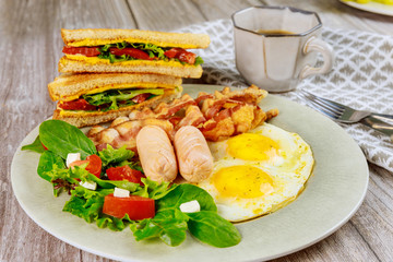 Traditional English breakfast with bacon, eggs, sausages, salad and grilled cheese toast.