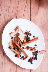Fragrant spices in a white plate on a wooden table.