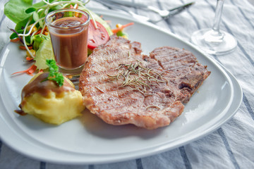 Grilled pork steak with mashed potatoes on a plate close-up.