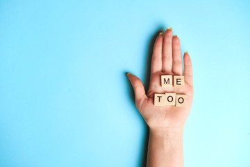 Phrase Me Too made of wooden letters in hand on blue background, top view. Stop sexual assault. Space left for text, copy