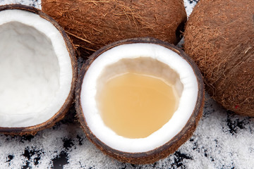 cut fresh coconut with real coconut milk on a background of coconut flakes. vitamin fruits. healthy food