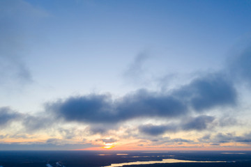 Fototapeta premium Aerial view sunset over the forest and lake. Top view. View from drone. Aerial top view cloudscape. Texture of clouds. View from above. Sunrise or sunset over clouds