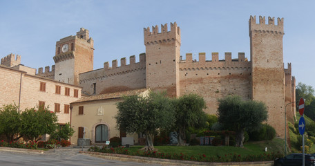 Fototapeta na wymiar External walls with towers and laces around the village of Gradara with olive trees and green lawn.