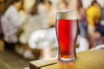 Glass of red beer stands on a table in a pub.
