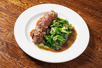 beef with roasted spinach on the wooden background
