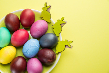 Colorful Easter eggs as an attribute of Easter celebration on the yellow plate.