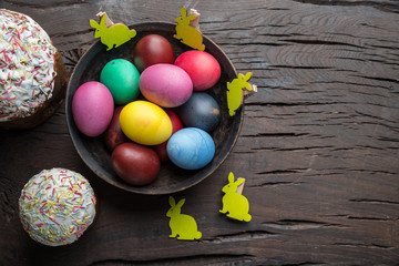 Colorful Easter eggs and Easter bread attributes of Easter celebration. Wooden background.